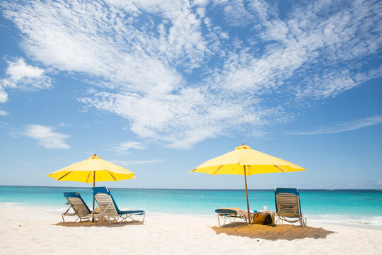 Scenic view of parasols and lounge chairs at beach against cloudy sky during sunny day