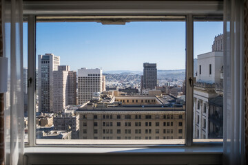 Buildings in city against sky seen through window