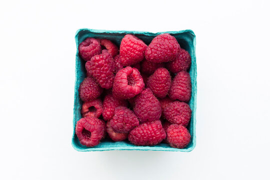 Overhead view of raspberries in container over white background