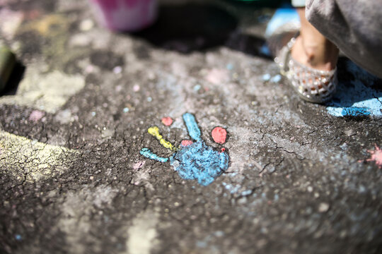 Close-up of girl by handprint on asphalt during sunny day