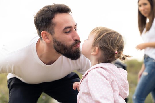 Close up photo of a father kissing his daughter outdoors