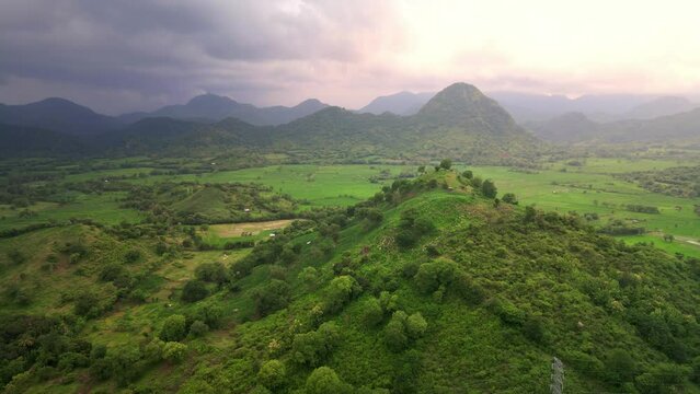Beautiful dolly drone shot of Terraced Rice Field at sunset with clouds in Sumbawa, Indonesia. agriculture land with mountain range at the background. Natural texture for background aerial footage.