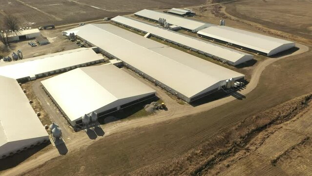 Drone shot of a hog confinement farm in Illinois with a worker driving a skid loader