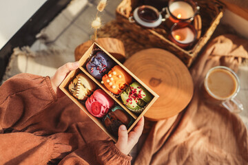 Box with different assortment of macaroons in hands