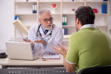 Fototapeta premium Young male patient visiting old male doctor