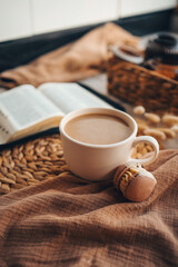 Cup of coffee and macarons, open bible in cozy home interior, good morning concept