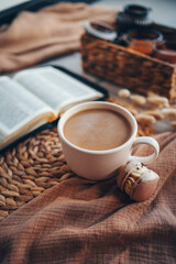 Cup of coffee and macarons, open bible in cozy home interior, good morning concept