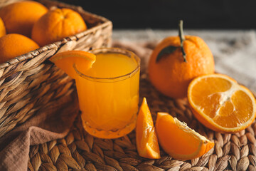 Glass of orange juice, sliced oranges, and a basket of oranges. The oranges are bright and fresh