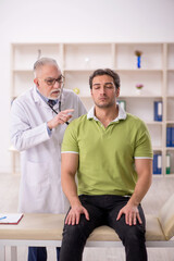 Fototapeta premium Young male patient visiting old male doctor
