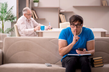 Obraz premium Young male student and his grandfather at home