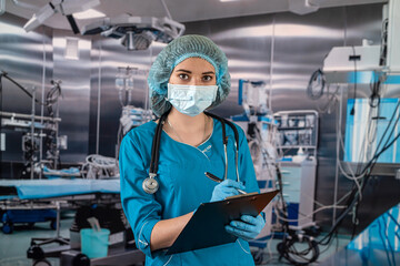 Fototapeta na wymiar doctor with stethoscope in operating room holding clipboard with operating room in background.
