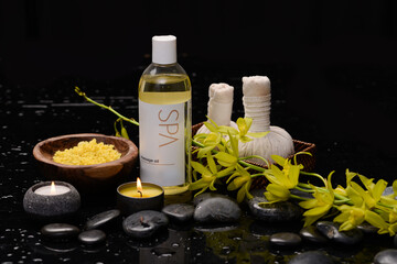 spa concept of white orchid with black zen stones and oil bottle ,salt in bowl, candle, spa ball on a wet background