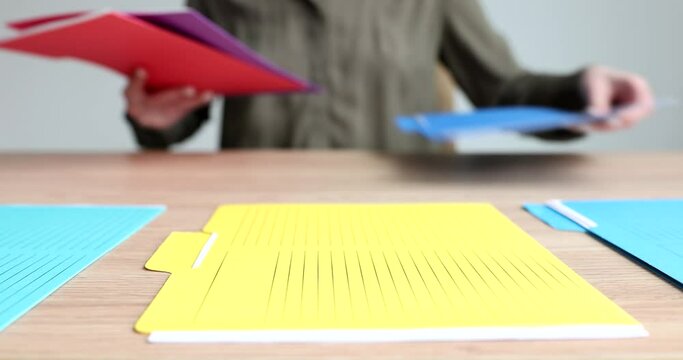 Secretary laying out multicolored folders with documents on table in office closeup 4k movie