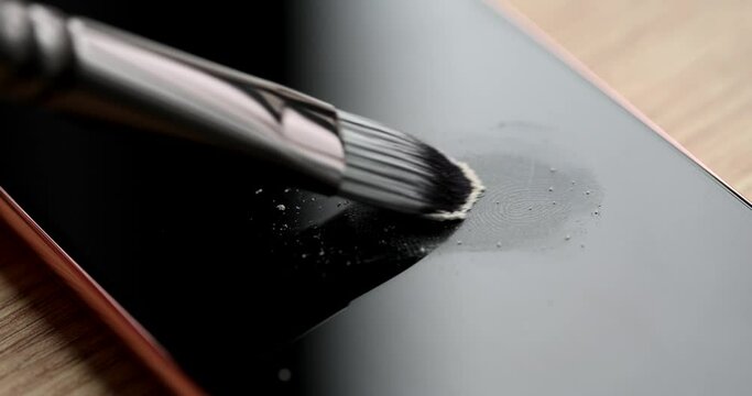 Forensic expert brushing talcum powder on fingerprint on mobile phone screen closeup 4k movie slow motion