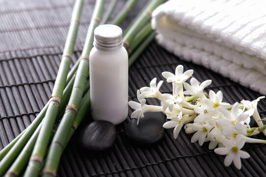 Healthy Concept, white flower ,oil bottle, towel, bamboo stem  , Spa with candle and stone spa on mat 