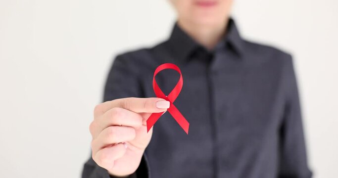 Woman hand holding red ribbon symbol of fight against hiv closeup 4k movie slow motion