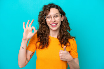 Fototapeta premium Young caucasian woman isolated on blue background With glasses and doing OK sign