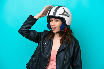 Young caucasian woman with a motorcycle helmet isolated on blue background doing surprise gesture while looking to the side