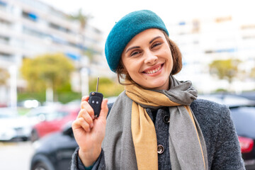 Brunette woman holding car keys at outdoors smiling a lot