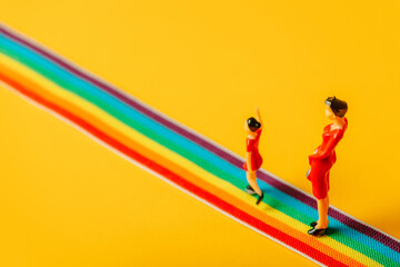 Fototapeta na wymiar little mother and daughter figures on the LGBT rainbow path