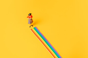 Adult woman figure stand on rainbow LGBT strip on yellow background