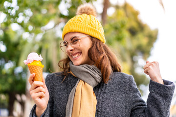 Brunette woman with a cornet ice cream at outdoors celebrating a victory