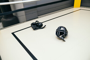 Protective kickboxing or boxing gloves and helmet on a ring floor