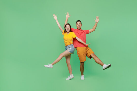 Full Body Overjoyed Cool Fun Happy Young Couple Two Friends Family Man Woman Wears Basic T-shirts Together Look Camera Raise Up Hands Isolated On Pastel Plain Light Green Background Studio Portrait.