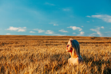 Blonde woman without clothes in wheat field in sunset time