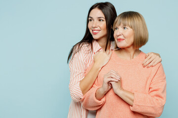 Smiling fun elder parent mom with young adult daughter two women together wear casual clothes look aside on workspace area mock up hugging isolated on plain blue cyan background. Family day concept.