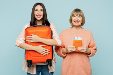 Elder parent mom young adult daughter two women wear casual clothes hold passport ticket bag isolated on plain blue background Tourist travel abroad in free time rest getaway. Air flight trip concept.