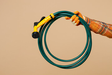 Close up cropped male holding in hand green hose with sprinkler isolated on pastel plain light...