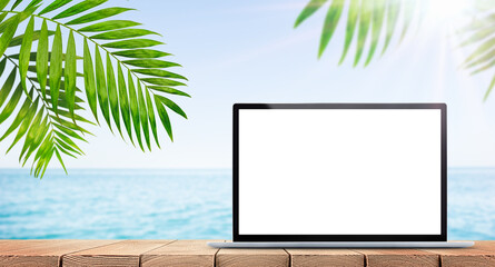 blank screen of a laptop standing on a table against the background of the sea, the concept of remote work