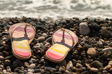 flip flops on beach and summer time. pebble beach at sunset