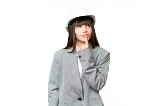 Little girl playing as a architect with helmet and holding blueprints over isolated background having doubts while looking up