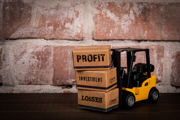 PROFIT LOSS INVESTMENT Concept. Miniature cardboard boxes on a wood and brick background