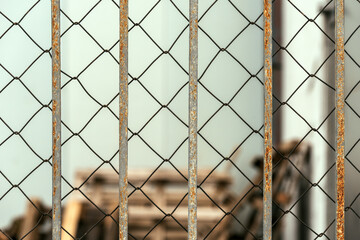 Chain link diamond pattern wire fence and worn metallic bars