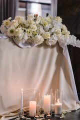 Table newlyweds covered a tablecloth in banquet area on wedding party. Table setting. Celebration concept. Wedding reception. Festive arch decorated composition flowers and candles in hall restaurant.