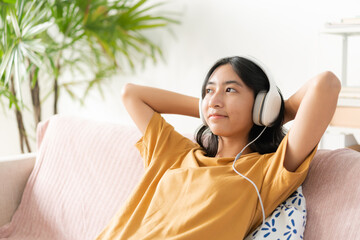 Asian teenager listening to music on smartphone with headphone enjoy at home