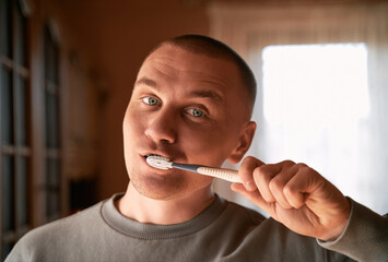 Portrait of a man with blue eyes cleaning teeth