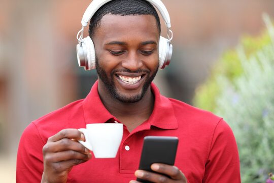 Happy black man listening to music drinking coffee