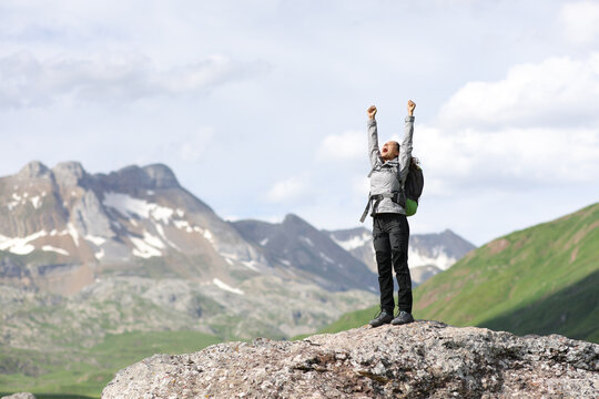 Excited hiker celebrating vacation raising arms in nature