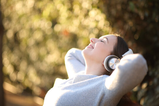 Woman relaxing listening audio with headphone in a bench