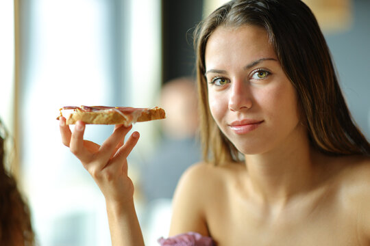 Woman looks at camera holding bread with jam
