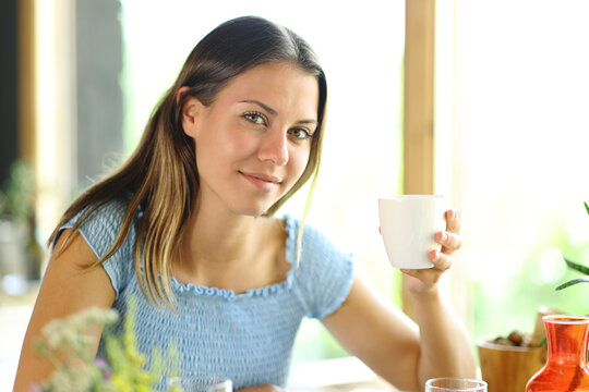 Woman holding coffee mug in a restaurant posing