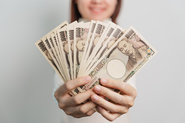 Woman hand holding Japanese Yen banknote stack. Thousand Yen money. Japan cash, Tax, Recession...