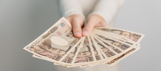 Woman hand holding Japanese Yen banknote stack. Thousand Yen money. Japan cash, Tax, Recession...