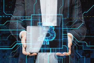 Close up of businessman hand holding tablet with glowing circuit bitcoin hologram on dark background. Cryptocurrency and finance concept. Double exposure.
