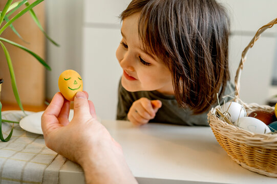 Smiling boy looking at decorated Easter egg at home