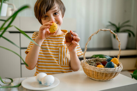 Smiling boy holding decorated Easter eggs at home